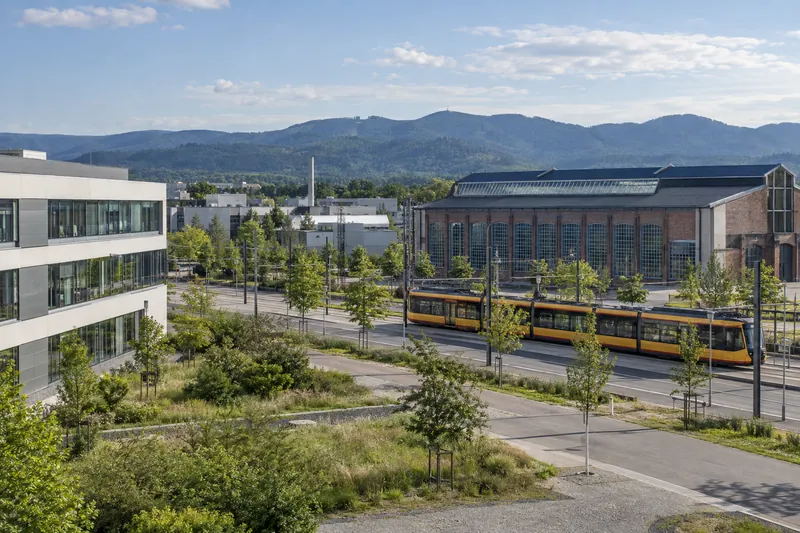 Bürogebäude und Industriehalle in der Rheinebene bei Karlsruhe, im Hintergrund die bewaldeten Höhen des Nordschwarzwalds