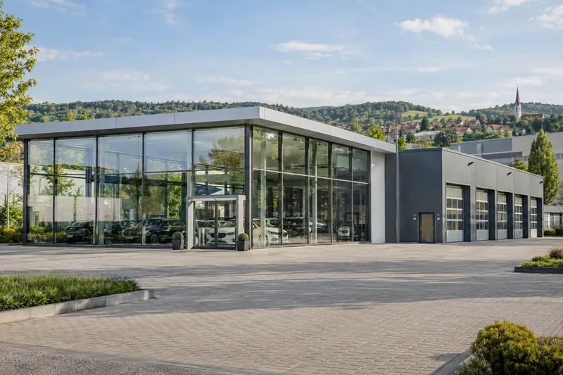 Autohaus mit Glasfront und Werkstattanbau in einem Gewerbegebiet bei Sindelfingen vor grünen Hügeln