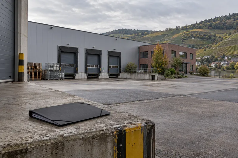 Zuliefererhalle mit Bürotrakt im Neckartal, im Hintergrund Weinberge