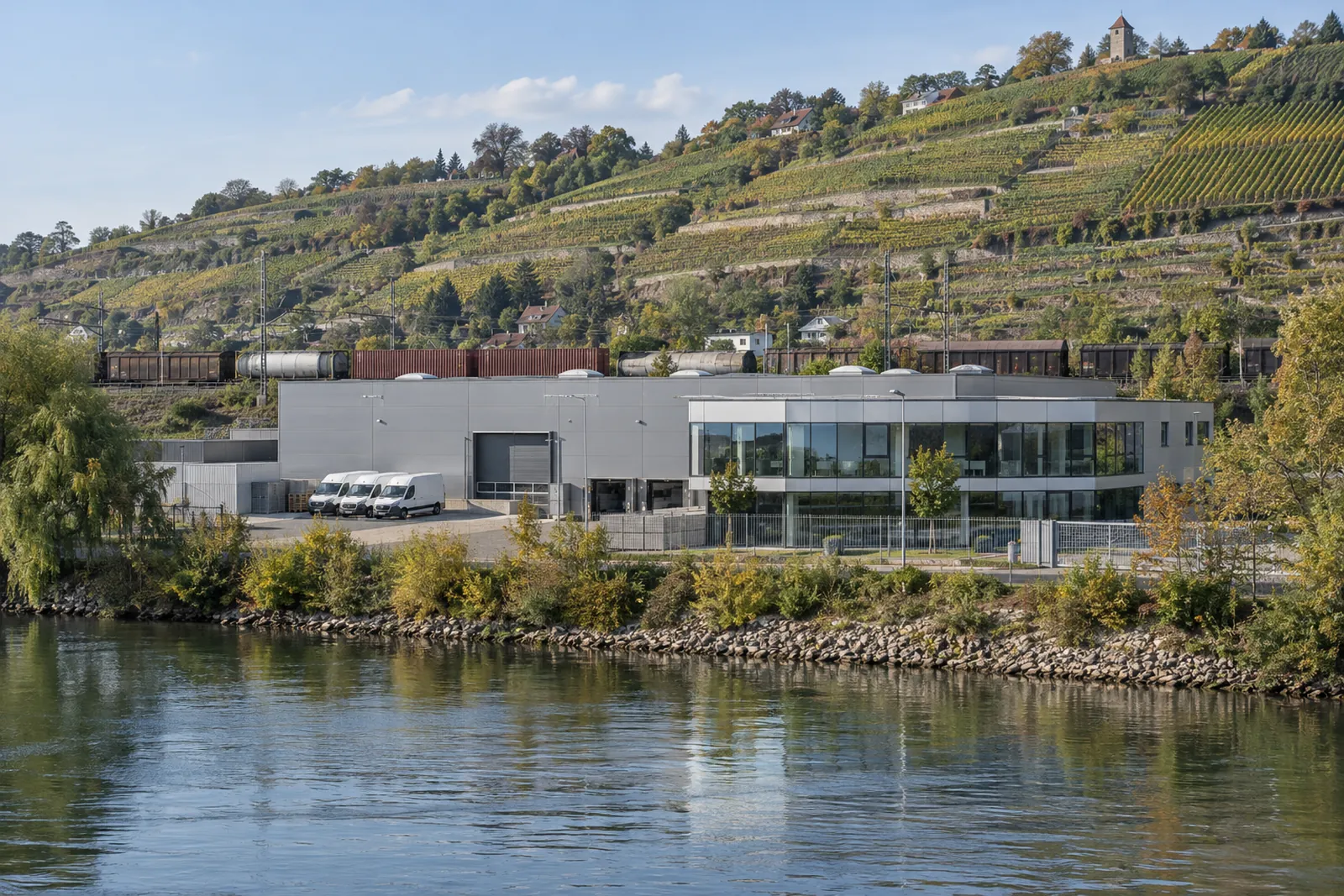 Gewerbehalle mit Büroanbau am Neckarufer, im Hintergrund Weinberghänge