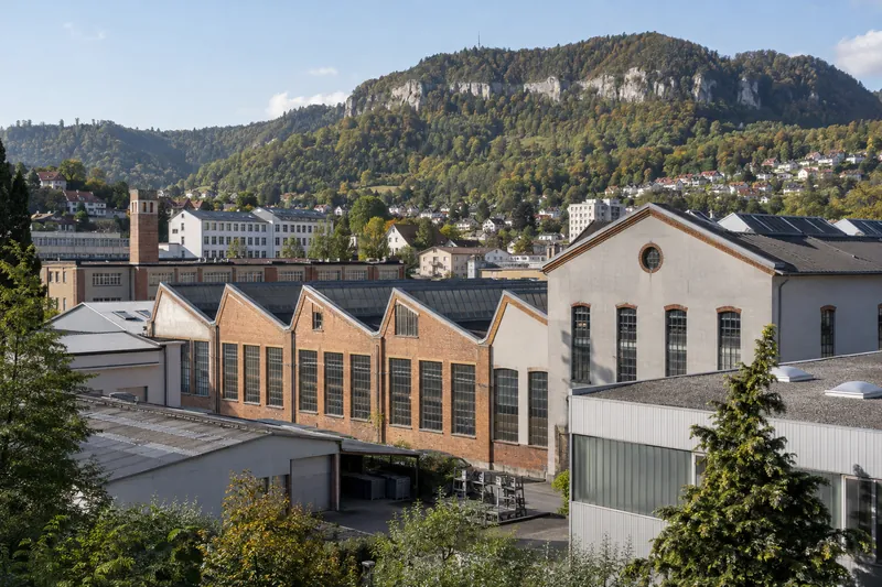 Ehemalige Fabrikgebäude mit Sheddächern in Albstadt vor bewaldeten Hängen der Schwäbischen Alb