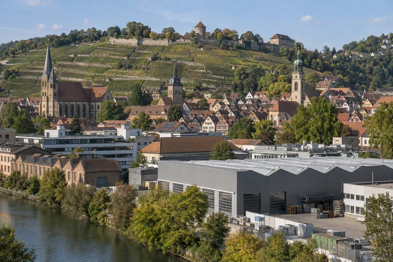 Gewerbebauten im Neckartal bei Esslingen mit der Altstadt und Weinbergen im Hintergrund