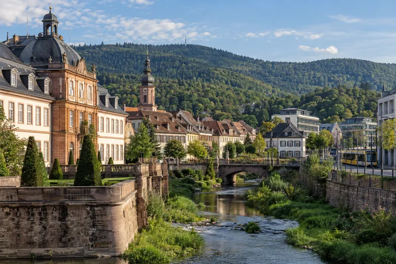 Barocke Altstadthäuser an der Alb in Ettlingen mit modernen Bürogebäuden und Schwarzwaldhügeln im Hintergrund