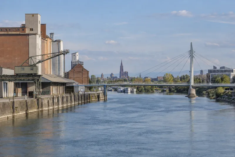 Lagerhallen am Rheinhafen mit Fußgängerbrücke und Straßburger Münsterturm in der Ferne