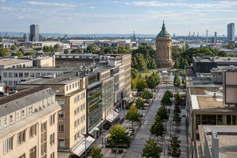 Geschäftshäuser in den Mannheimer Quadraten mit Wasserturm im Hintergrund und Hafenhallen am Rhein