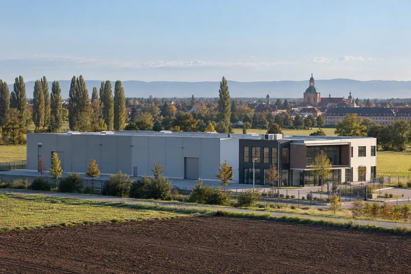 Gewerbehalle mit Bürotrakt am Stadtrand von Rastatt, im Hintergrund die barocken Dächer der Altstadt in der Rheinebene