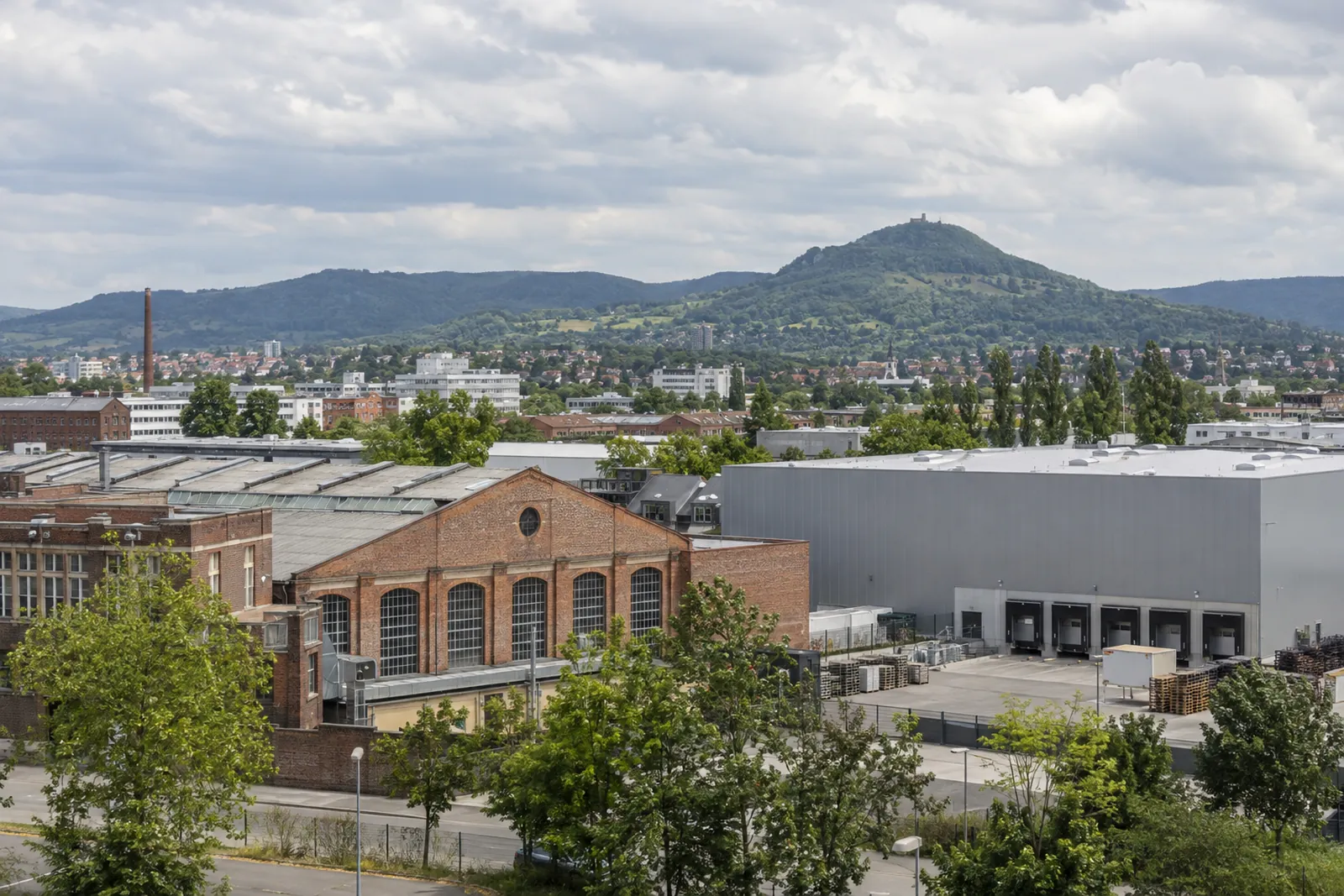 Ehemalige Fabrikhalle aus Backstein neben einer modernen Gewerbehalle in Reutlingen, im Hintergrund der Achalm